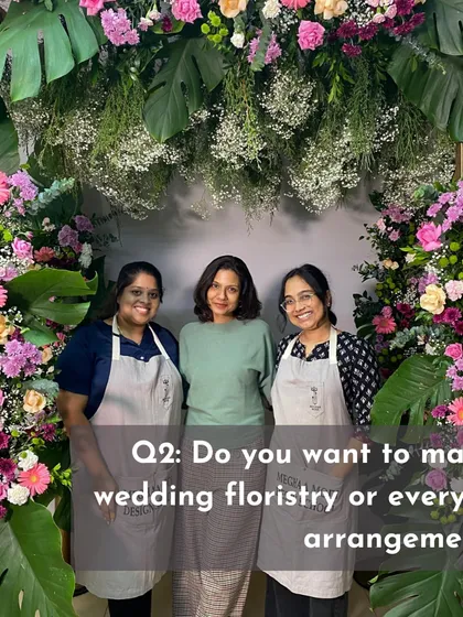 Three students stand behind a massive floral arch they created. This shows the scale and ambition of projects we tackle in the professional and event design courses.