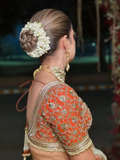 A detailed shot of the bridal hairstyle, a classic bun adorned with fragrant jasmine flowers (gajra). This is a timeless element of traditional Indian bridal beauty.