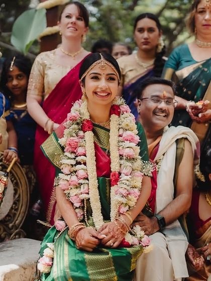 The bride, surrounded by family and guests from two cultures, smiles brightly during her wedding ceremony.
