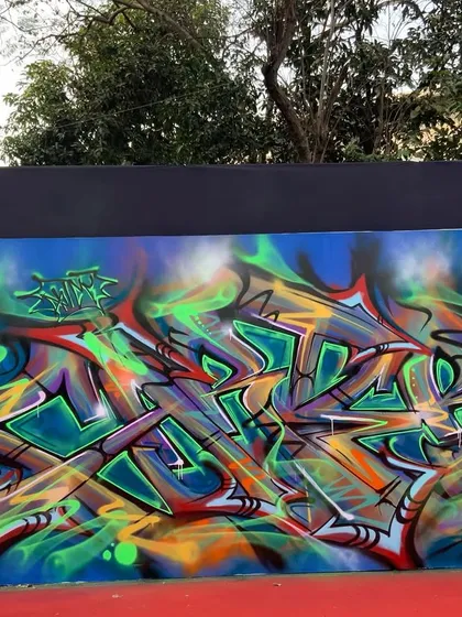 The finished wildstyle piece from the Kula festival. The vibrant greens, oranges, and purples pop against the blue background, creating a complex and eye-catching mural.