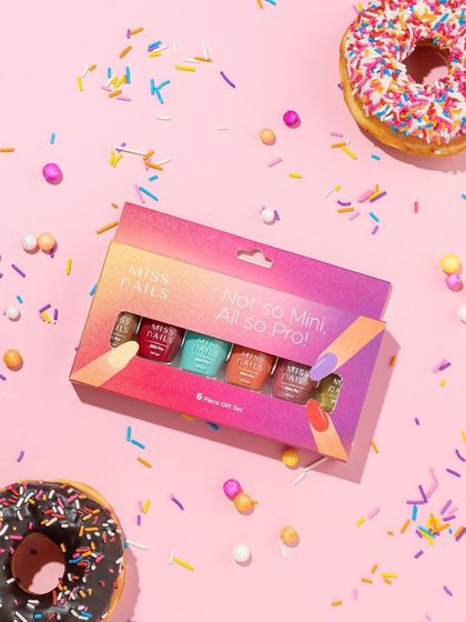 Fun and playful! This flatlay for a mini nail polish set uses donuts and sprinkles to create a celebratory, dessert-themed vibe that is perfect for a younger, trend-focused audience.