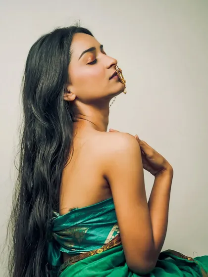 A serene and sensual profile shot, with the model's eyes closed, emphasizing her graceful neckline and the traditional nath.