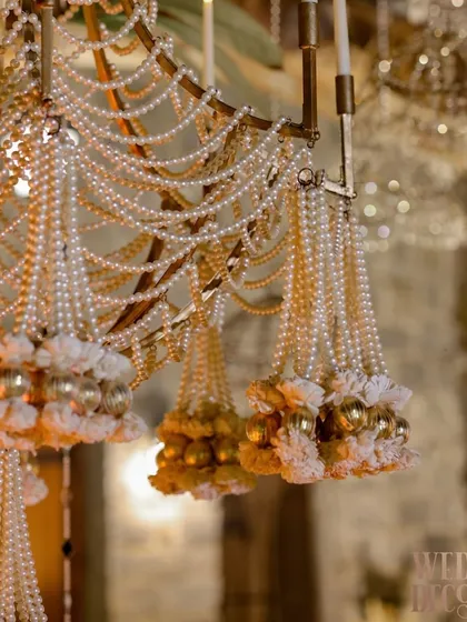 It is the exquisite details that define luxury. This close-up showcases a custom-designed chandelier, where countless strands of pearls and delicate floral elements come together to create a masterpiece of light and opulence for a truly grand affair.