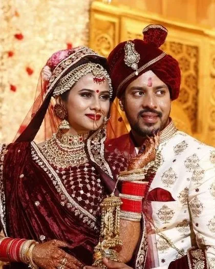A close-up of our maroon velvet bridal lehenga, paired with a groom's sherwani in a complementary off-white shade with maroon floral motifs. Renting a coordinated set from us saves you time and ensures a flawless match.