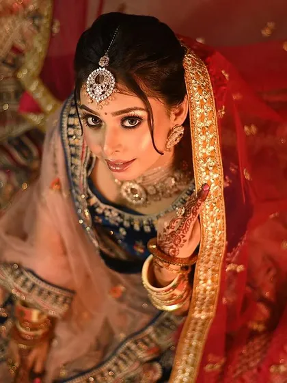 A creative angle for a unique bridal portrait. This top-down view captures the bride's confident gaze and the beautiful spread of her lehenga, creating an artistic and memorable shot.