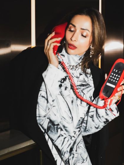 Malaika Arora in a candid moment with the red phone prop. These unposed shots often have the most personality.