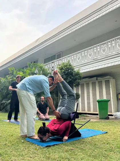 Assisting a student in a challenging backbend using a chair. This moment represents the culmination of my journey, from a nervous beginner to a confident guide for others.