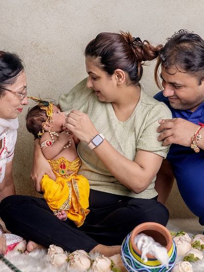 Janmashtami is a celebration for the whole family. Here, parents and a grandparent share a loving moment with their newborn Krishna, creating a cherished multi-generational photograph.