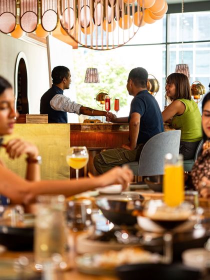 A view from the dining room to the bar, where guests are enjoying conversations and expertly crafted cocktails. The atmosphere is always lively and welcoming.