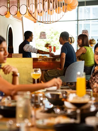 A view from the dining room to the bar, where guests are enjoying conversations and expertly crafted cocktails. The atmosphere is always lively and welcoming.