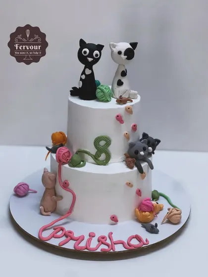 A two-tier cat theme cake for an 8th birthday. This vanilla truffle cake is decorated with playful fondant cats and balls of yarn.