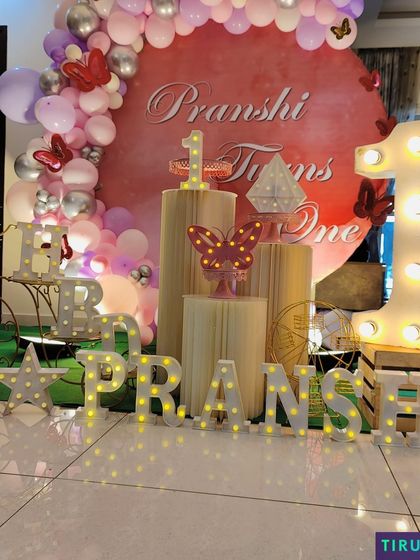 A close up of the butterfly themed first birthday, highlighting the illuminated name and number props that add a special glow to the setup.