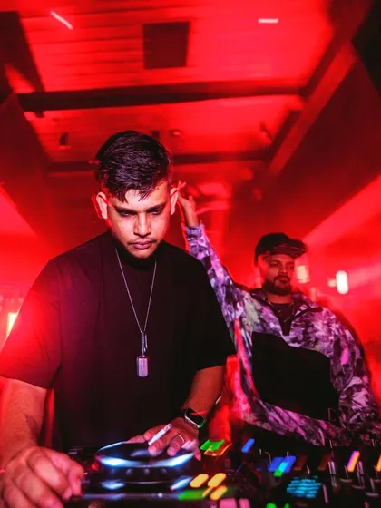 An intense shot of me and another DJ under red lights, focused on delivering a powerful set.