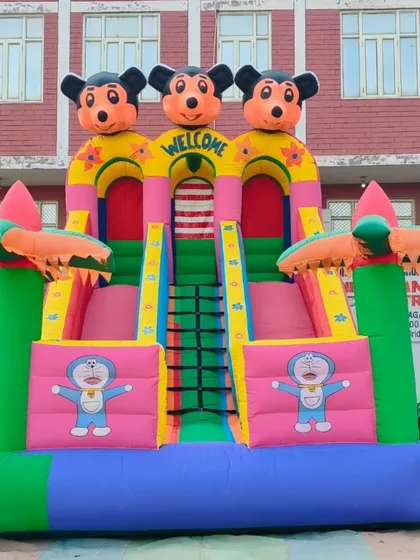 A bright and colorful 3-lane bouncy slide featuring Mickey Mouse and Doraemon. The palm tree designs on the side give it a fun, tropical feel.