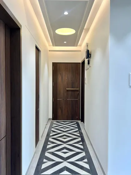 A simple yet elegant passageway. The design is elevated by the striking black-and-white geometric runner pattern created with floor tiles, leading the eye towards the main living spaces.