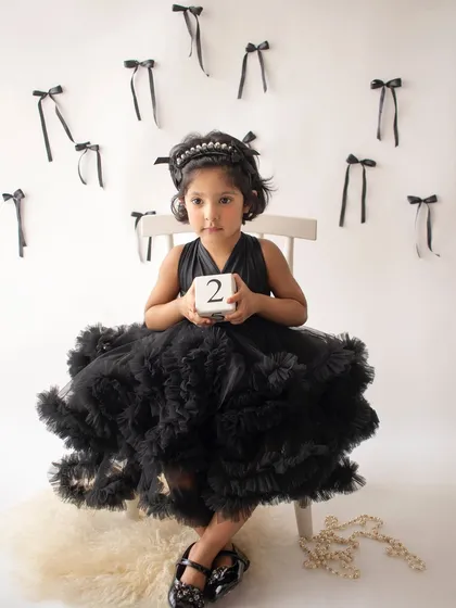 Celebrating turning two with a stylish photoshoot. This little girl is wearing a beautiful black tulle dress, holding a number block to mark her milestone.