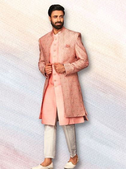 This textured pink sherwani is a great example of modern groomswear. Paired with a matching kurta and white trousers, it's a stylish and confident look.