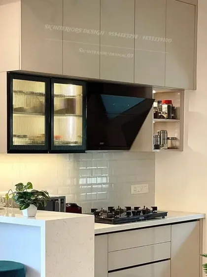 This shot highlights the integrated chimney and the glass-fronted cabinet with internal lighting in a modern kitchen setup.