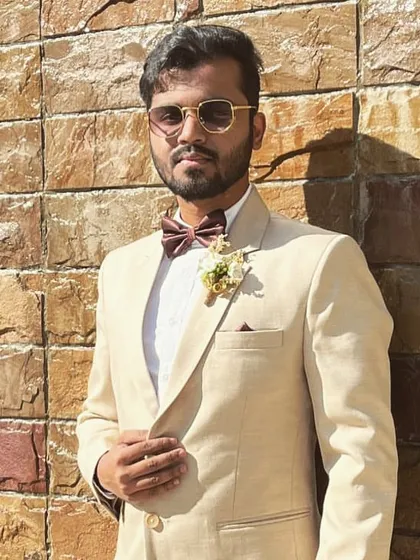 The groom's party deserves to look sharp too. Here is a closer look at a custom boutonniere, or spray, with a cream-colored flower and subtle greenery, designed to complement the groomsman's beige suit and bow tie for a Bombay Catholic wedding.