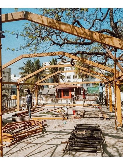 The wooden frame of the rooftop kitchen being assembled under a large tree. This shows the initial phase of a lightweight structure designed to sit gently on an existing building.