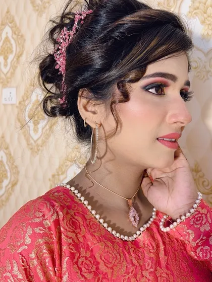 A side profile of the party look, highlighting the soft curls framing the face and the elegant makeup. The pink dress and accessories tie the whole look together.