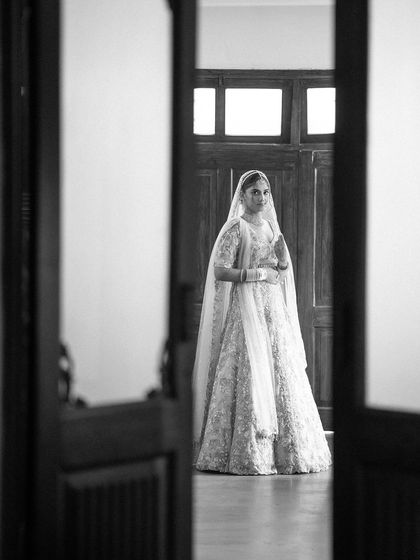 A beautiful black and white portrait of a bride standing in a doorway, the natural light creating a soft and elegant look.