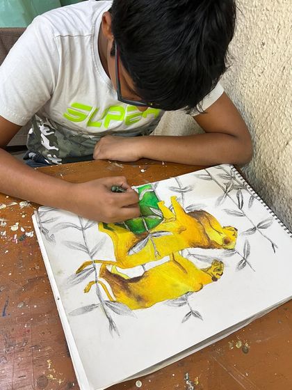 A young artist using oil pastels to create a powerful drawing of lions, learning about animal anatomy and color blending.