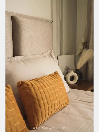 Detail of the bedside in the master bedroom. The combination of a textured cushion, a simple vase, and a fluted wall panel creates a composition of quiet elegance.