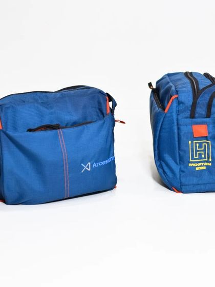 A side-by-side view of two custom sling bags, one for Arcesium and one for another client, showcasing different branding styles on a similar product.