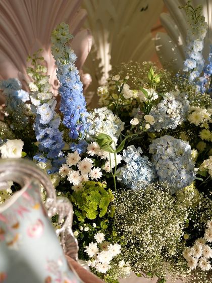 A beautiful mix of blue delphiniums, white daisies, and green hydrangeas.