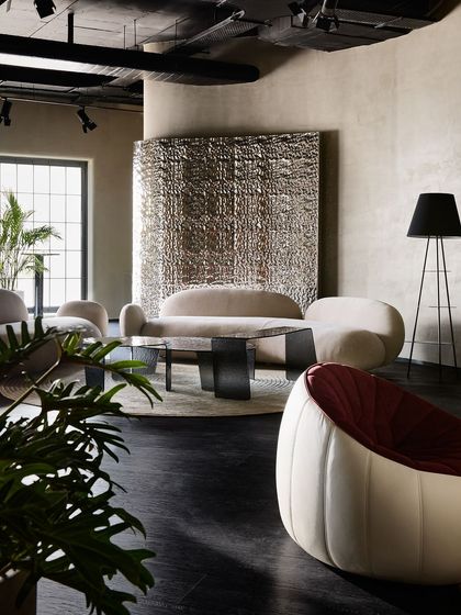 Another angle of the minimalist living area, showing a plush beanbag-style chair that adds a touch of playful comfort. The large, metallic wall panel creates a dramatic focal point.