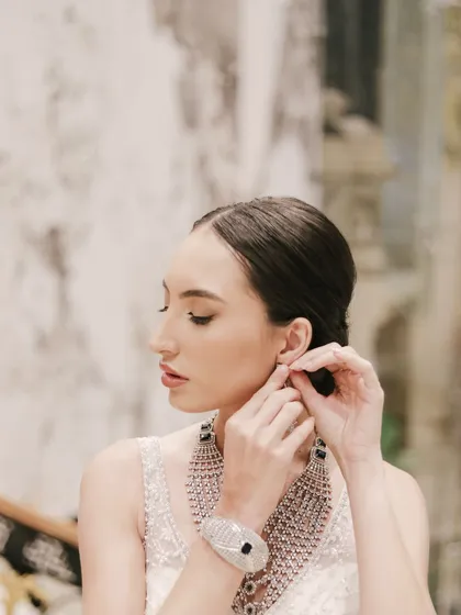 A delicate profile shot of a model adjusting her earring during a jewelry photoshoot. This candid-style photo beautifully captures the elegance of the diamond jewelry.
