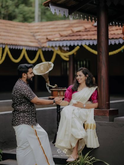 A couple in traditional Kerala attire sharing a dance in a classic courtyard, with a vintage gramophone adding to the charm.