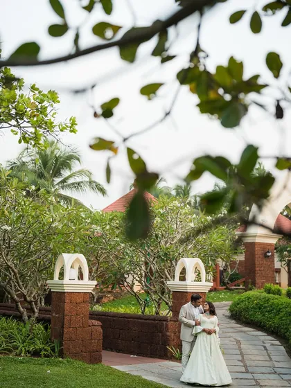 A romantic shot of the couple framed by the lush greenery and architecture of the Goa resort.