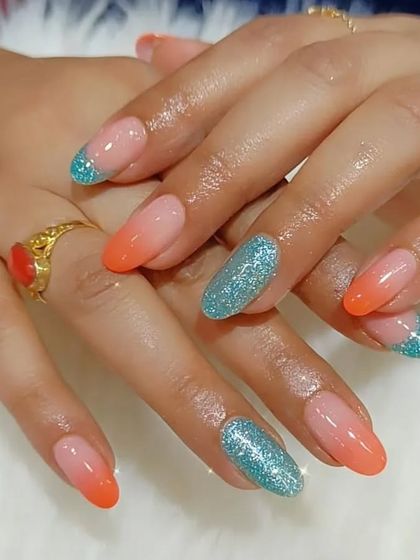 A playful mix of orange ombre and sparkling turquoise glitter nails, a perfect color combination for a fun, summery look.