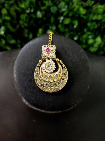 The maang tikka for this set, featuring the same crescent design to tie the whole look together.