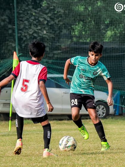 A one-on-one challenge near the corner flag, with both players focused on the ball.