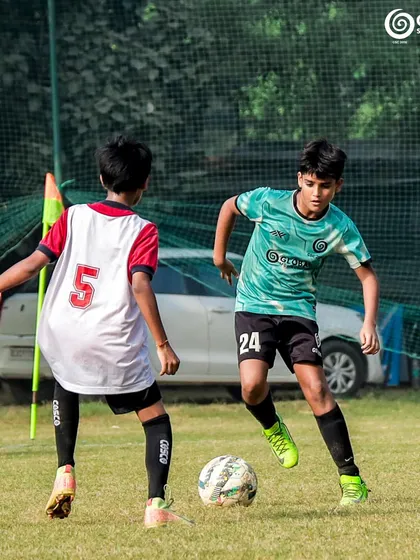 A one-on-one challenge near the corner flag, with both players focused on the ball.