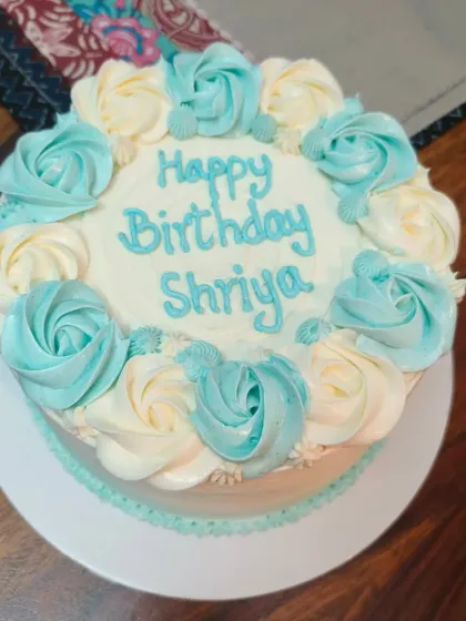 A simple floral cake with blue and white rosettes.