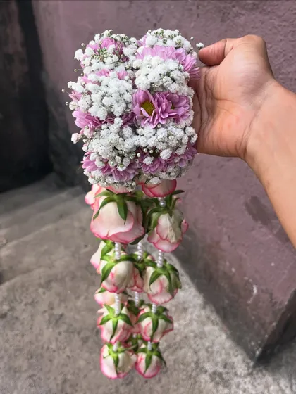 A pair of handcrafted floral handcuffs with attached kaliree. This unique design combines the bracelet and kaliree into one piece, made with pink roses and baby's breath.