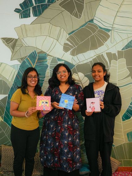 Three participants show off their unique cat-themed paintings, a wonderful souvenir from their day.