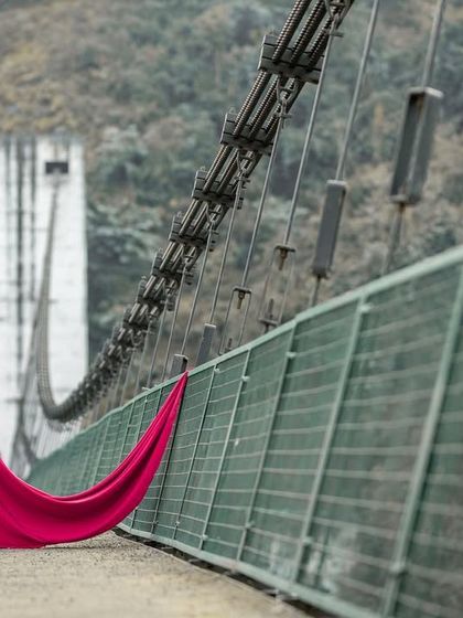 A beautifully framed shot of the couple on a bridge, showcasing the stunning location and their elegant attire for their pre-wedding session.