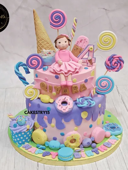A sweet and vibrant two-tier Candyland doll cake. This pineapple cake is a colorful treat, decorated with fondant lollipops, donuts, and an ice cream cone, perfect for a fourth birthday.