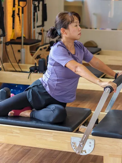 A client performs a mermaid stretch on the Reformer. This exercise is fantastic for stretching the side body, improving spinal mobility, and relieving tension in the obliques and shoulders.