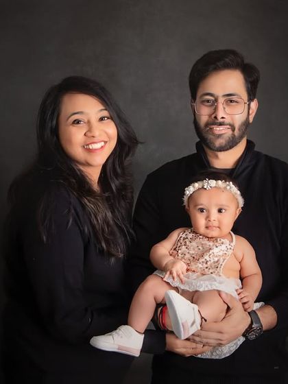 A classic family-of-three portrait. The simple black outfits and dark background create a timeless and elegant look that will never go out of style.