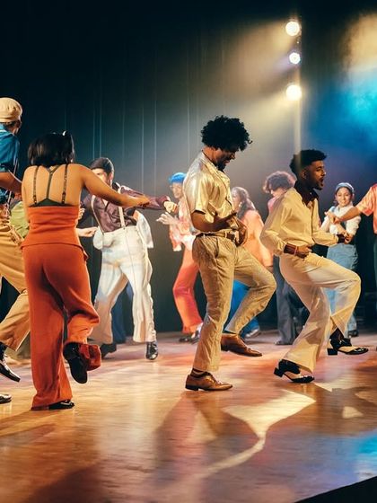 A beautiful shot capturing the flow and movement of multiple dancers across the stage during a vibrant performance.