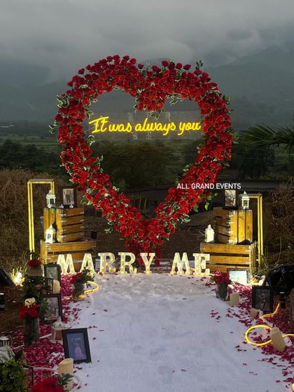 The setup just after sunset, when the lights take full effect. The warm glow from the neon sign, marquee letters, and lanterns creates a deeply romantic and inviting atmosphere for the proposal.