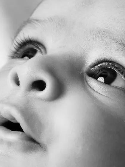 Sometimes, the smallest details are the most precious. This artistic black and white close-up captures the wonder in a baby's eyes, long lashes, and tiny features that you'll want to remember forever.