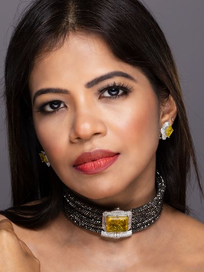 A clean, sharp close-up of a model wearing a modern choker necklace with a large yellow center stone and matching earrings. This type of shot is ideal for e-commerce and product listings.