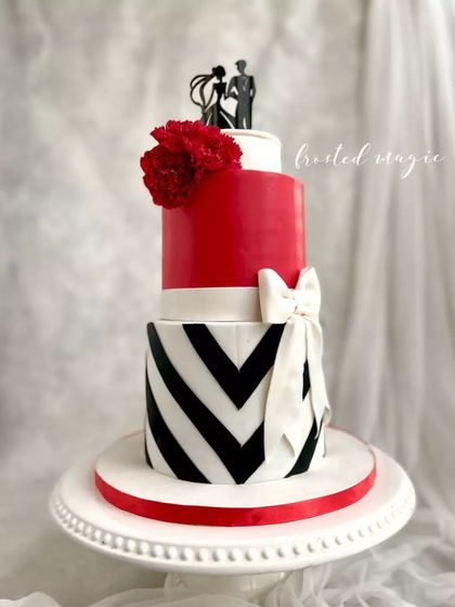 A classic and bold engagement cake in red, white, and black. This design features a sharp chevron pattern and a big white bow, and even includes special slots to hold the couple's engagement rings.